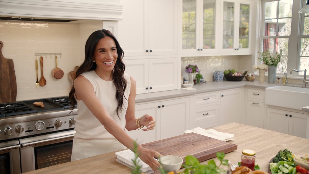 A woman in a white dress stands in a white kitchen