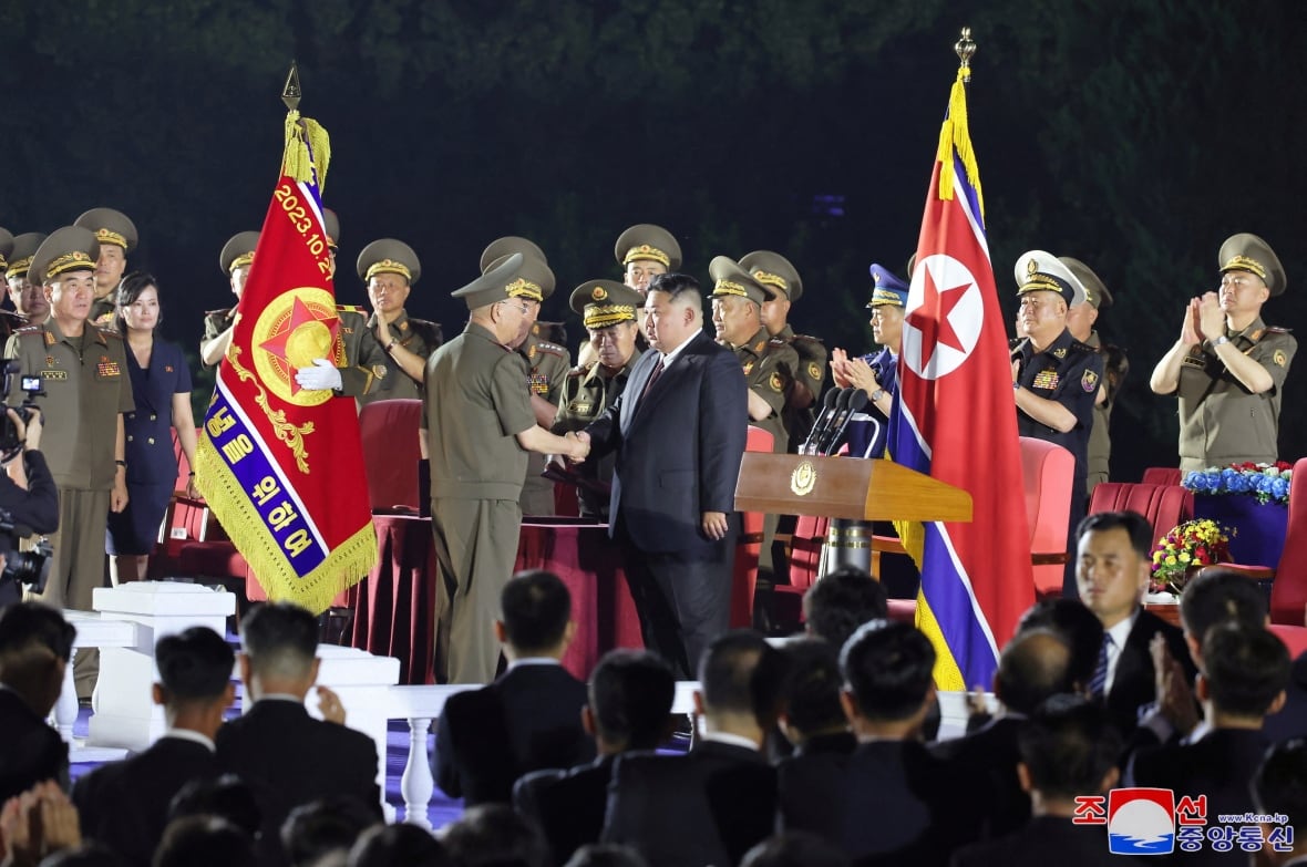 Auf der Bühne erscheinen mehrere asiatische Männer, die meisten tragen Militäruniformen mit Nationalflaggen im Hintergrund. Auch ein asiatischer Mann im Anzug erschien auf der Bühne.